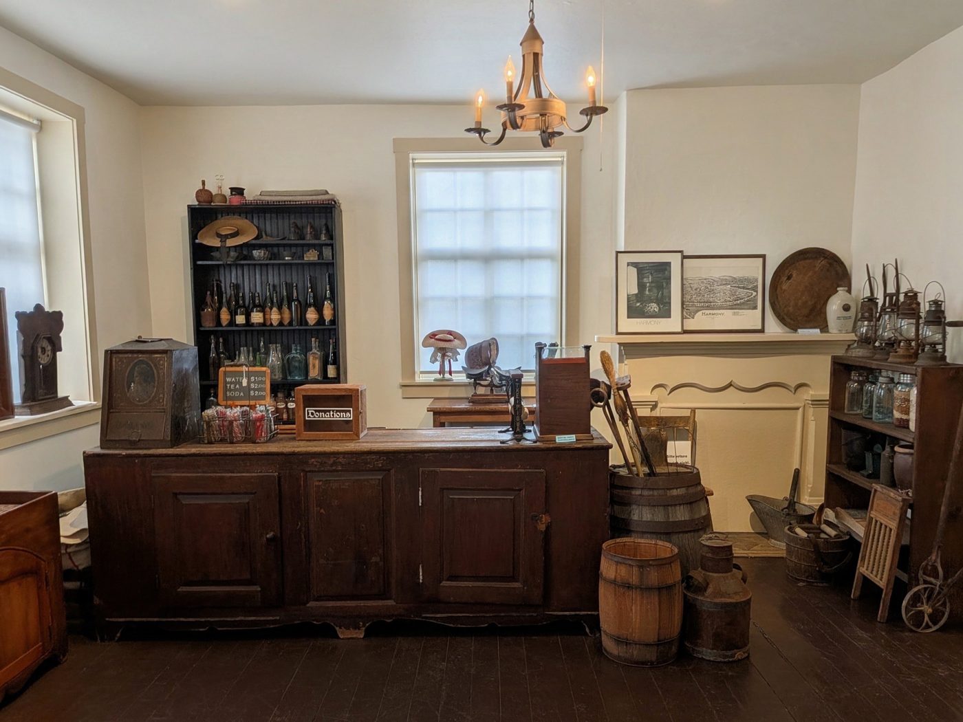The museum shop: a long wooden counter, shelves of old bottles and lanterns, and barrels beneath a candle chandelier