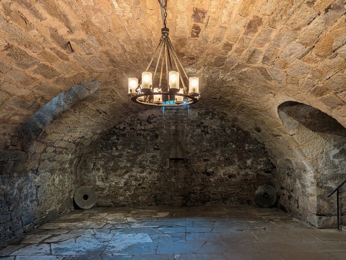 The vaulted stone wine cellar of 1809 beneath the museum, lit by a candle chandelier