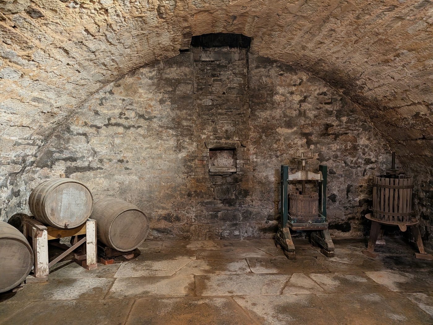 Old barrels and wooden wine presses against the cellar's stone walls
