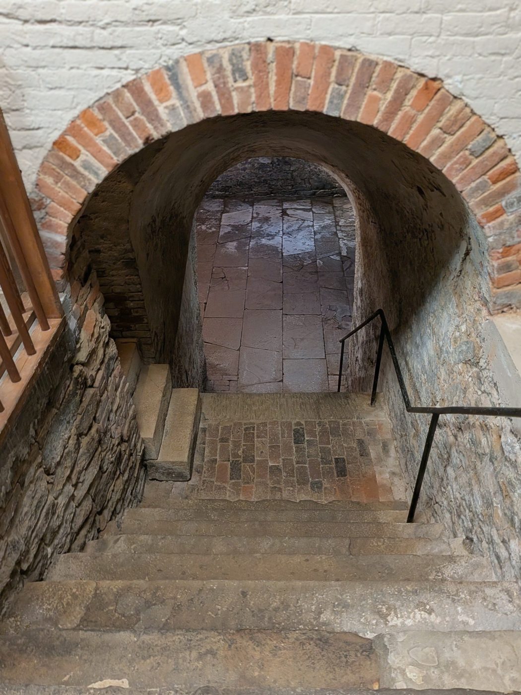 Stone steps under a brick arch leading down into the 1809 wine cellar